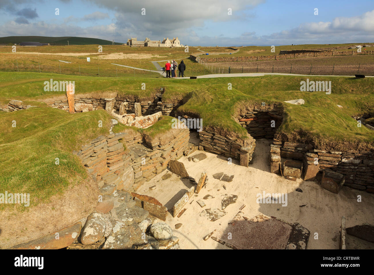 Gli scavi delle antiche abitazioni preistoriche nel villaggio neolitico di Skara Brae con Skaill house al di là delle Isole Orcadi Scozia UK Foto Stock