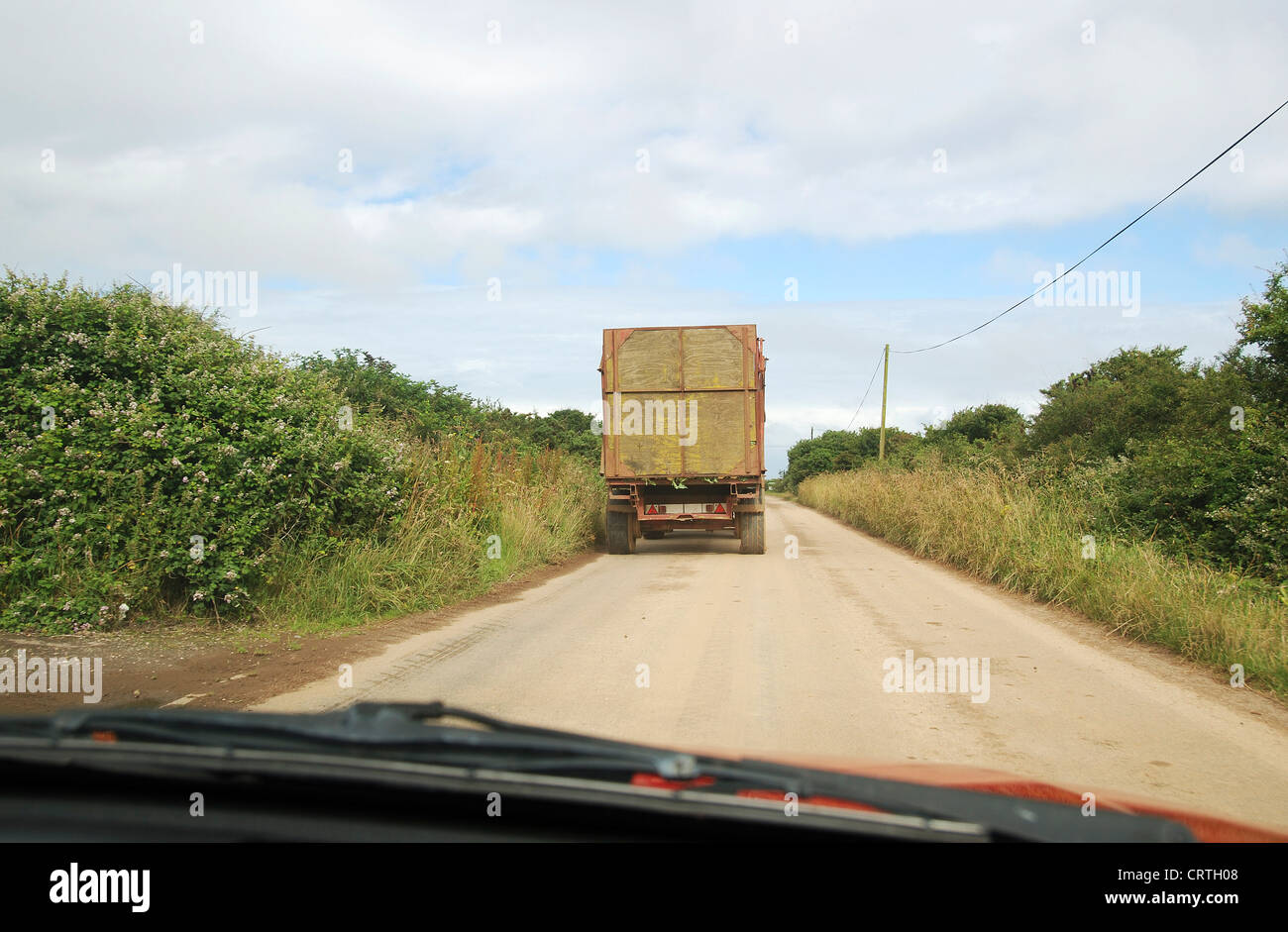 Una guida auto dietro un veicolo agricolo in un paese Lane, Regno Unito Foto Stock