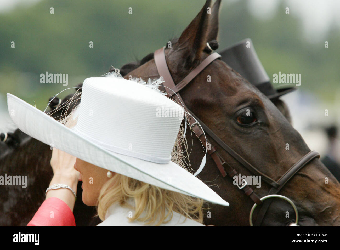 Gli spettatori con un cappello di fronte a cavallo presso il Royal Ascot Racecourse Foto Stock