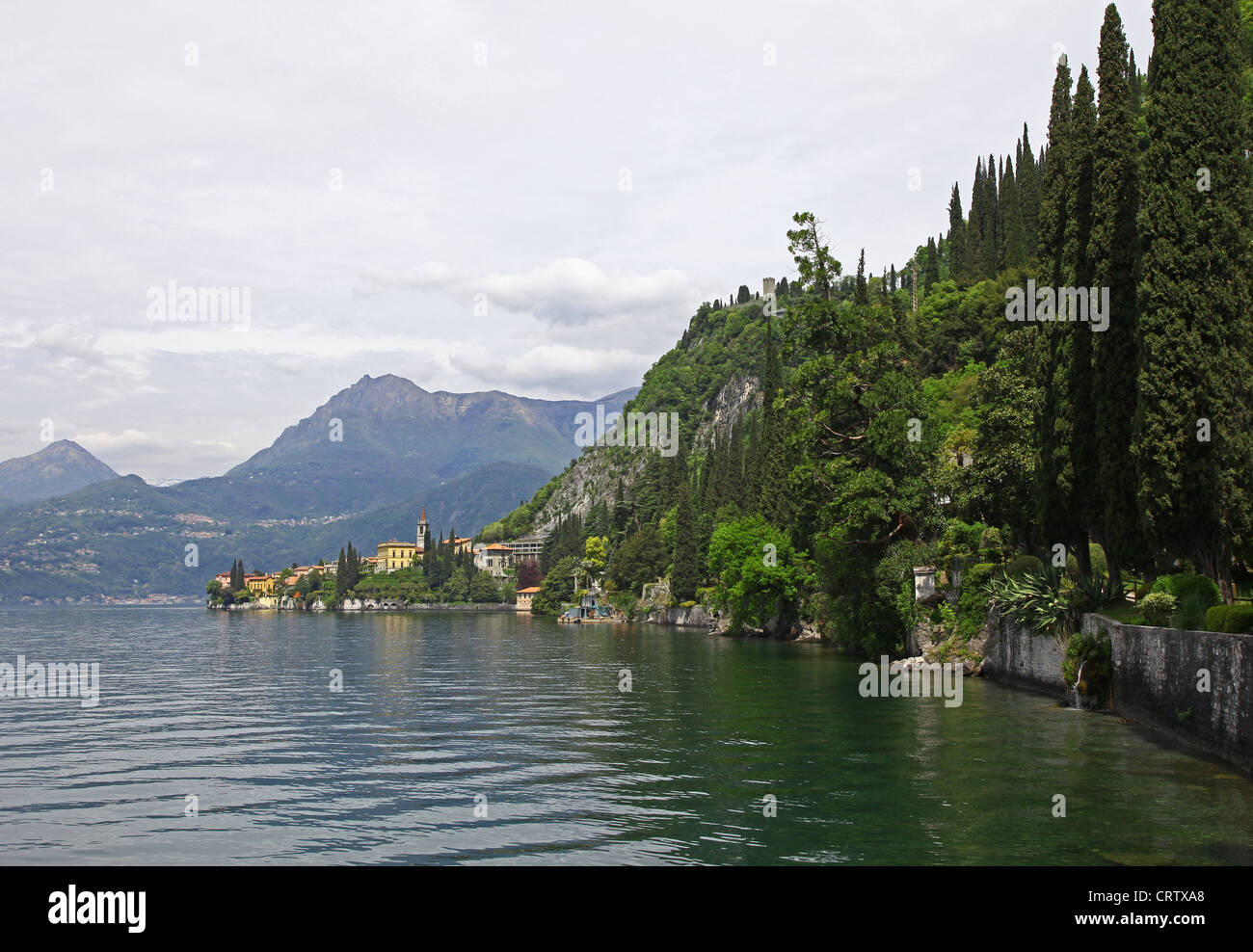 Guardando verso i giardini di Villa Cipressi dai giardini di Villa Monastero Varenna e il castello di Vezio visto sul lago di Como Foto Stock
