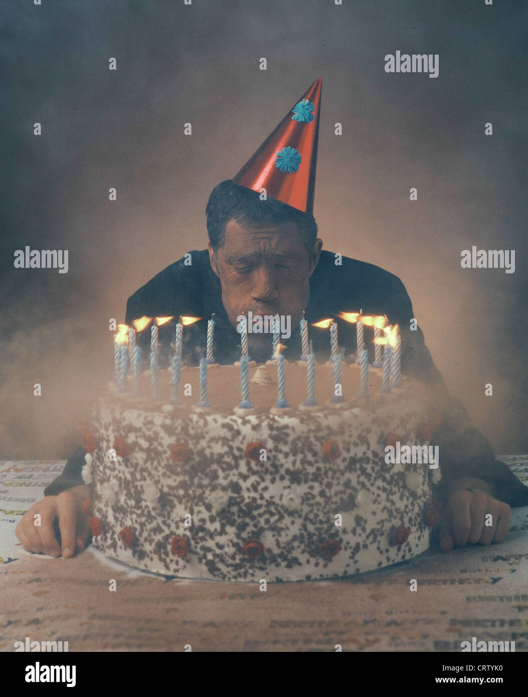 Un uomo si brucia le candele della sua torta di compleanno Foto Stock