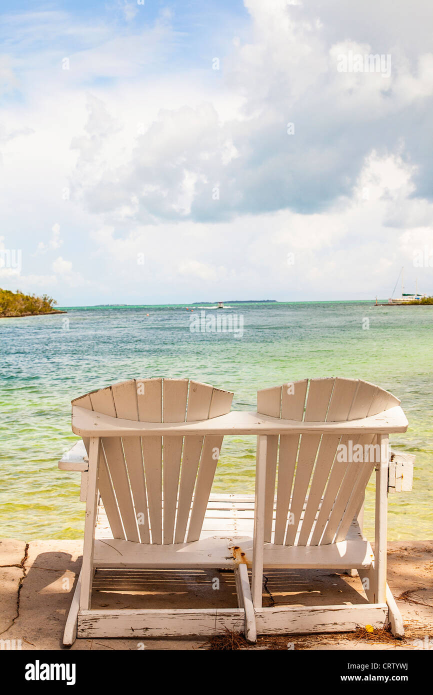 Due sedie che si affacciano sul mare di Abaco nel piccolo villaggio di speranza comune, gomito Cay Abacos, Bahamas. Foto Stock