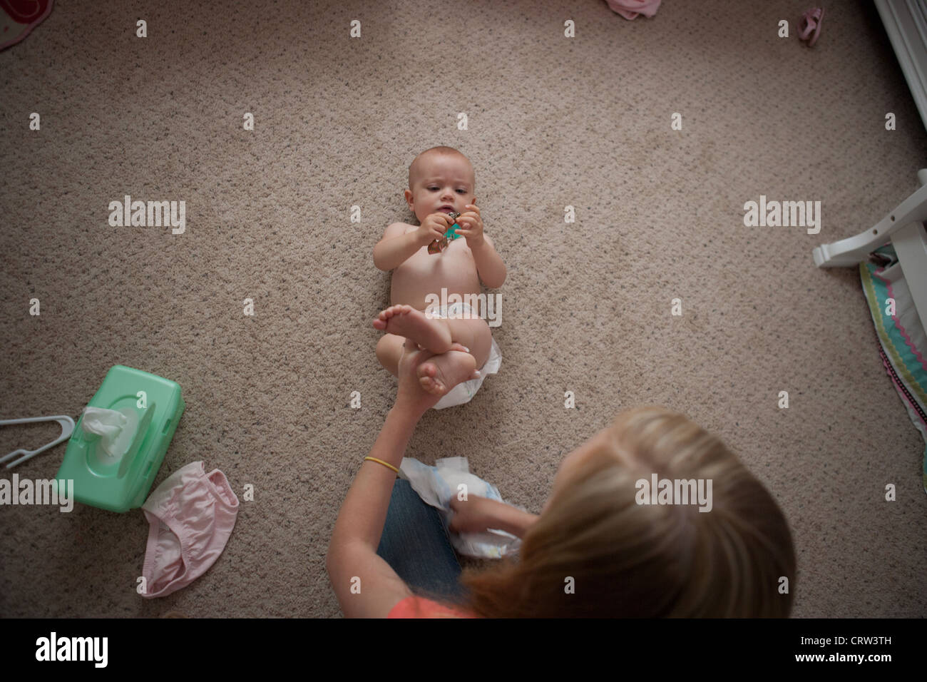 Vecchia sorella cambiando pannolino per dieci mesi di età la sorella a casa. Foto Stock
