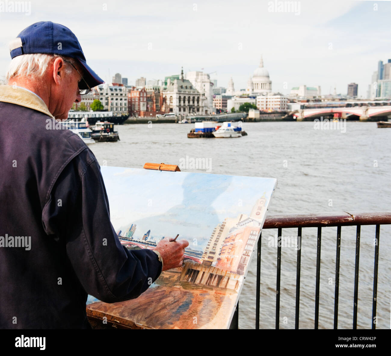 Un maschio dai capelli grigi artista dipinge il panorama della città di Londra skyline dalla banca del sud del Tamigi in una limpida giornata estiva Foto Stock