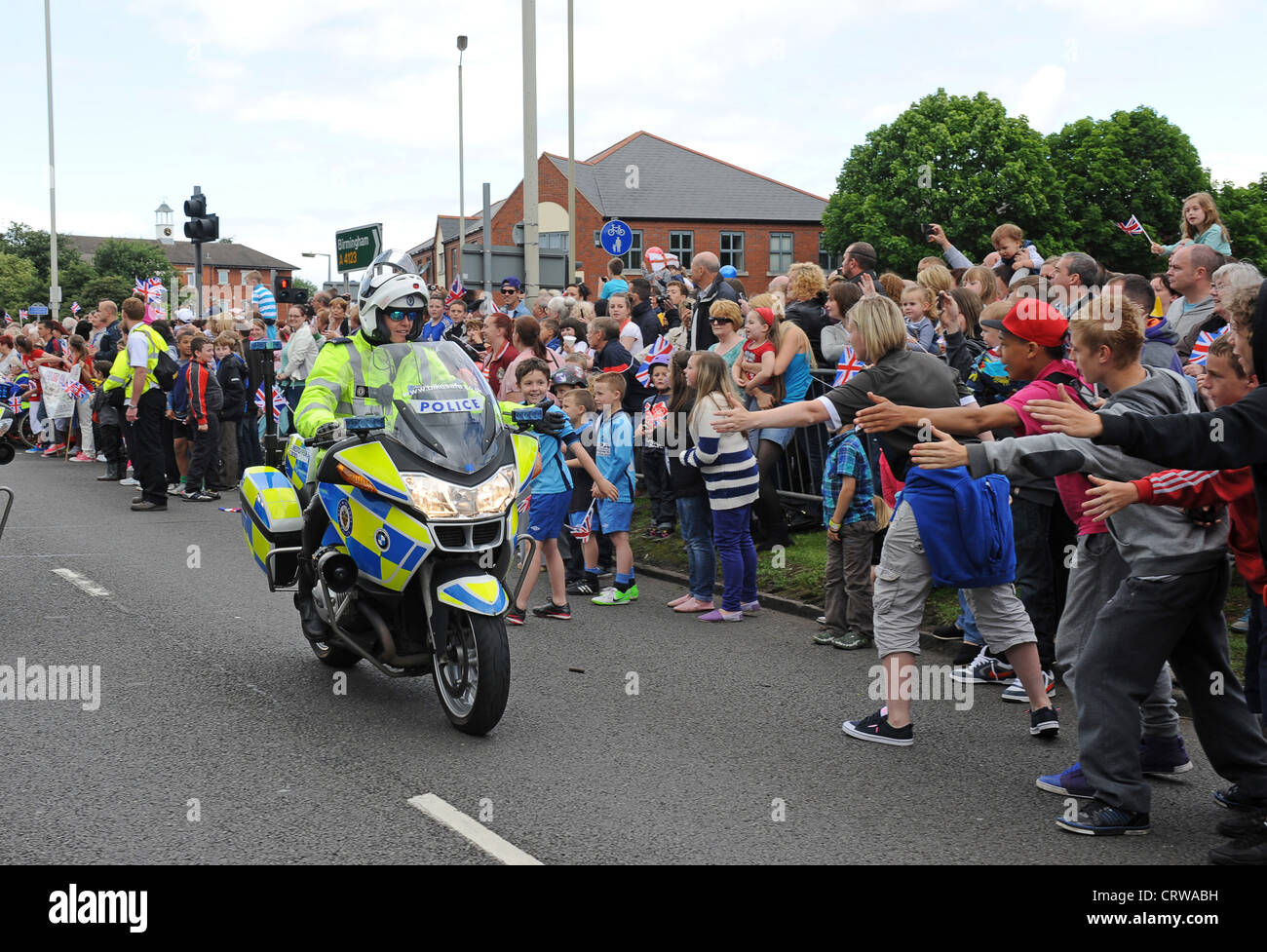 La polizia motociclista fiving alta o mano Tapa con gli spettatori per la Torcia Olimpica in halifax hx6 2np Regno Unito Foto Stock