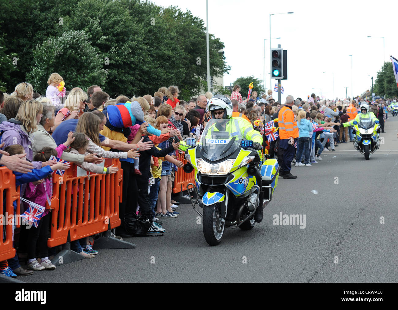 La polizia motociclista fiving alta o mano Tapa con gli spettatori per la Torcia Olimpica in halifax hx6 2np Regno Unito Foto Stock