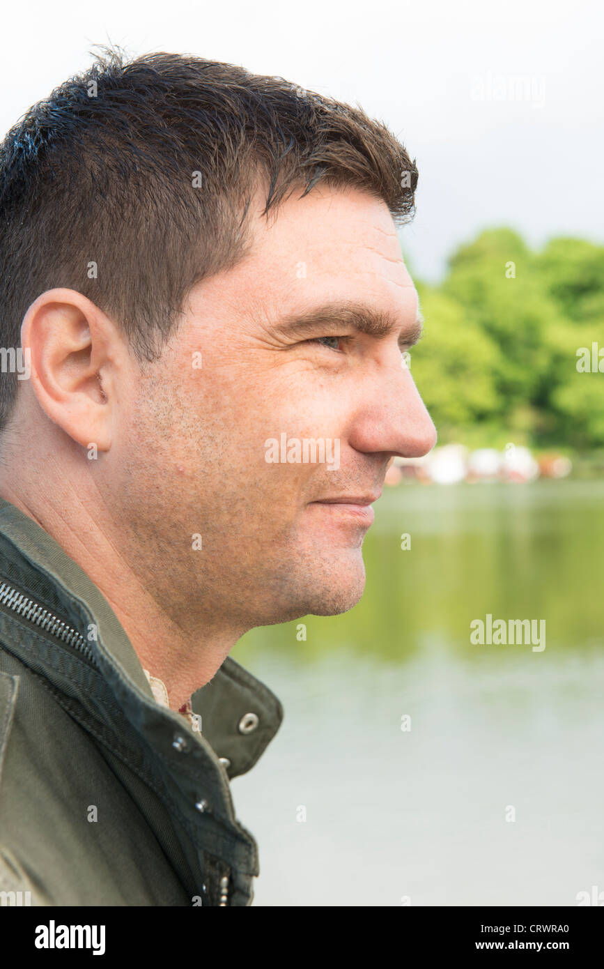 Close up di un uomo guarda il paesaggio da un lago Foto Stock