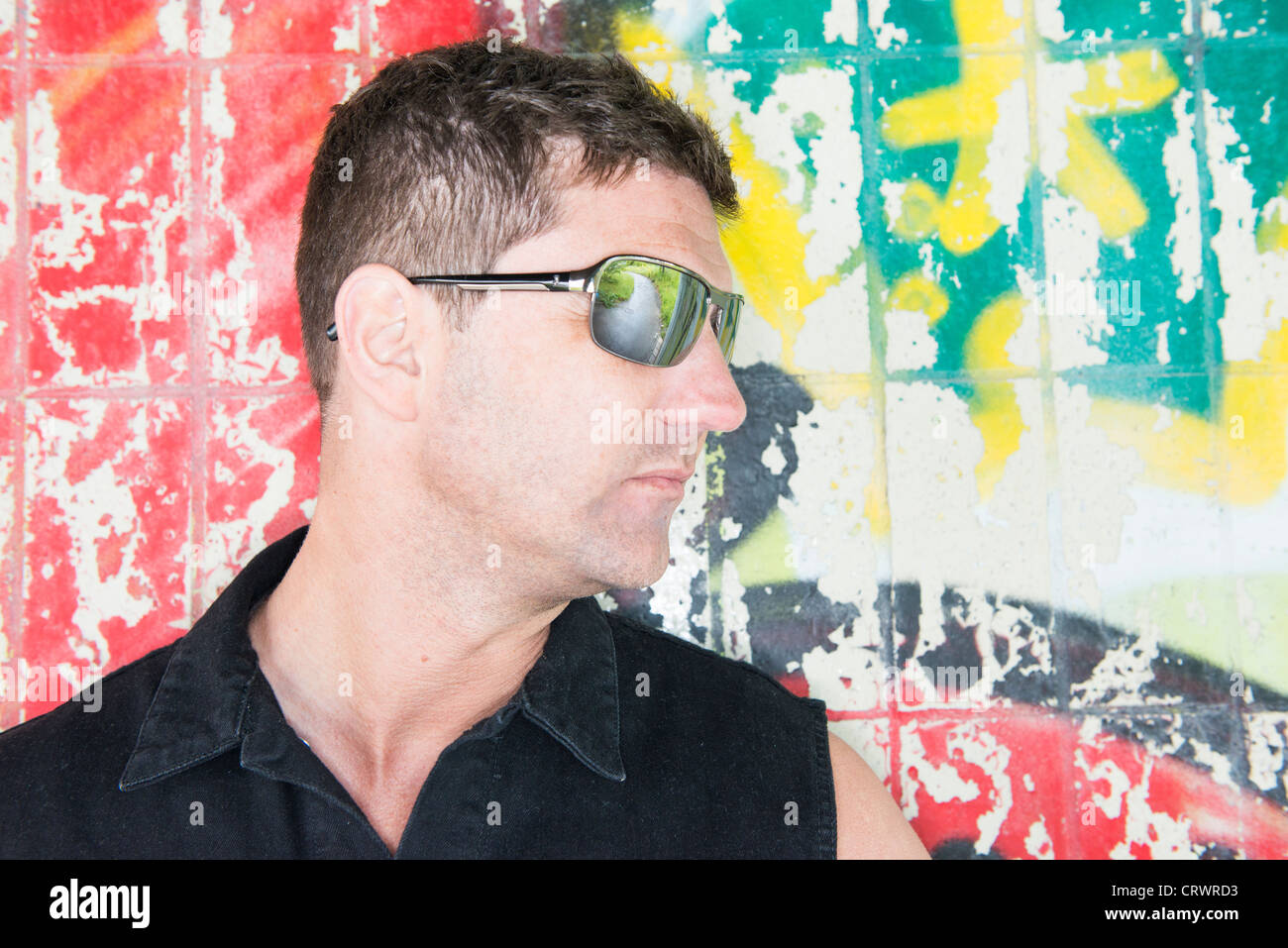 Cool ragazzo indossa occhiali da sole in un decaduto urbano. La strada che conduce al verde della natura si riflette nel suo occhiali da sole. Foto Stock