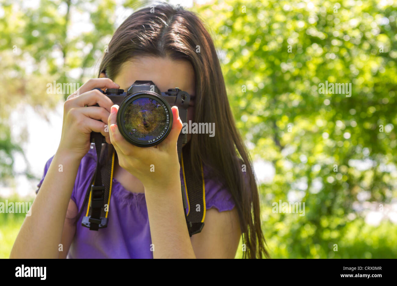 Ritratto di brunette girl, rendendo le foto in estate green park. Foto Stock
