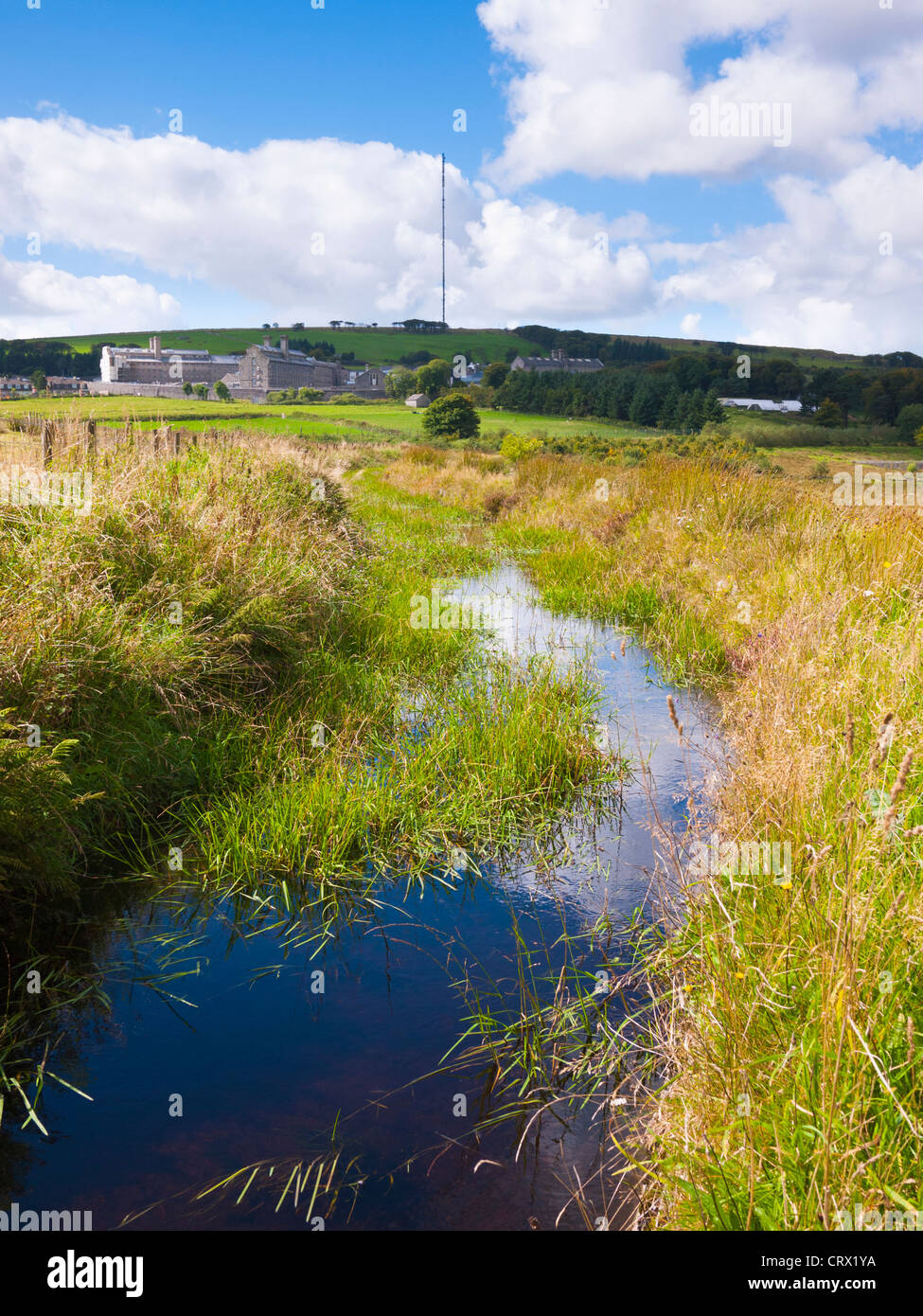 Devonport Leat vicino a Princetown nel Parco Nazionale di Dartmoor, Devon, Inghilterra. In lontananza si può vedere la prigione di Dartmoor. Foto Stock