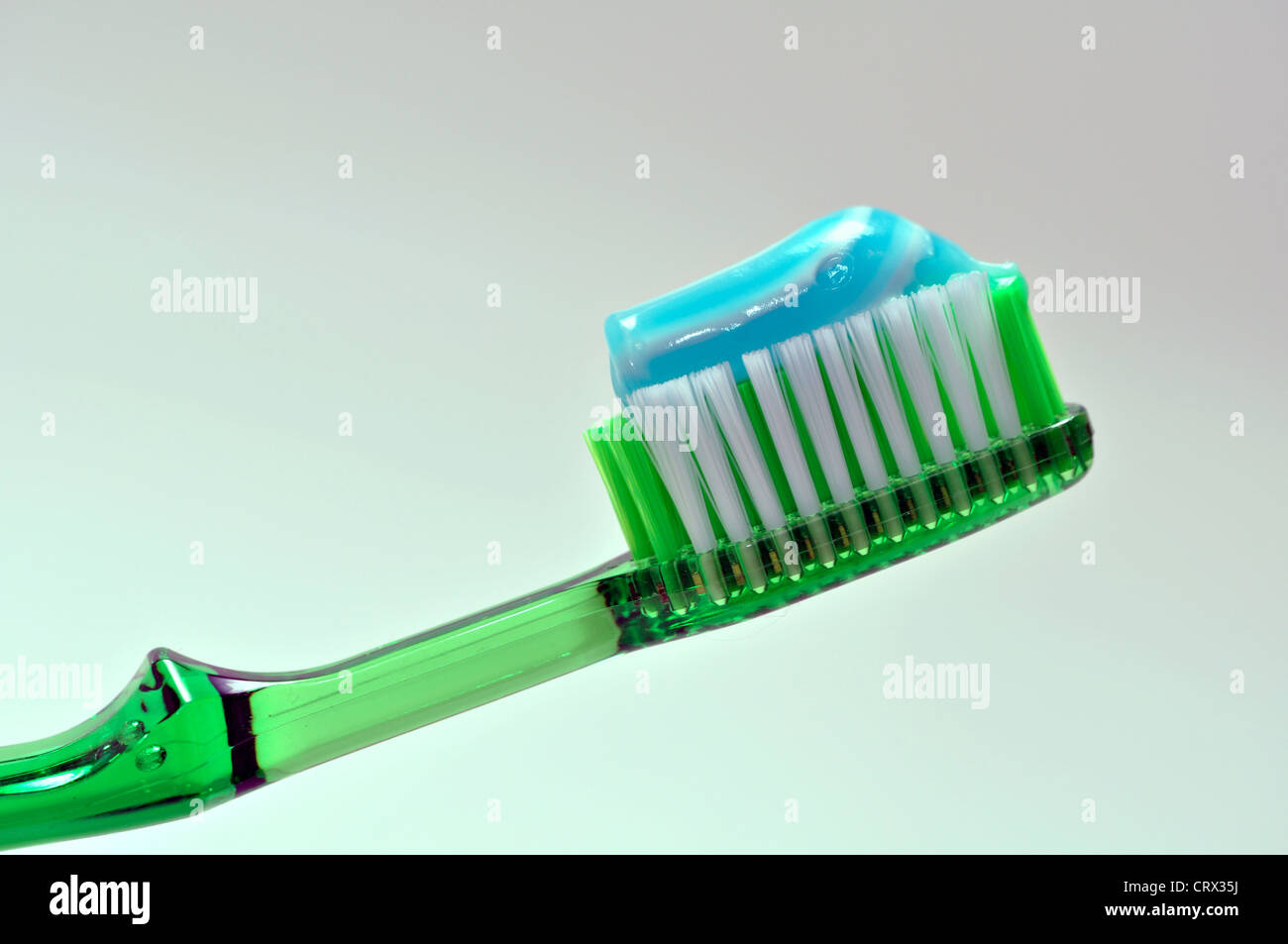 Un verde spazzolino da denti con blu e bianco pasta dentifricia su di esso. Foto Stock
