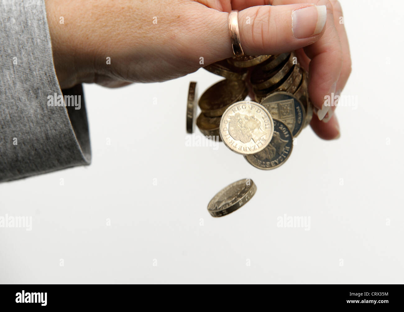 Pound monete in caduta da una mano femminile Inghilterra Regno Unito Foto Stock