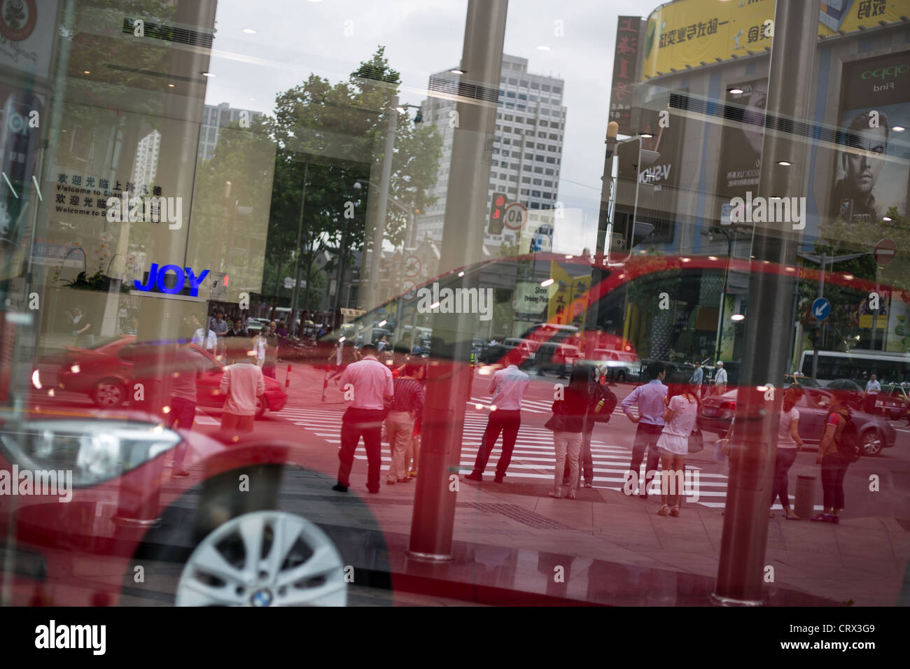 Gli acquirenti e i pedoni riflessa nella concessionaria auto, in Cina a Shanghai. Foto Stock