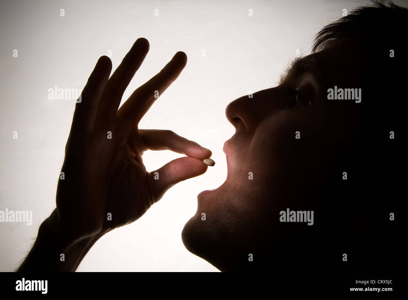 La silhouette di un giovane uomo di prendere una pillola. Foto Stock