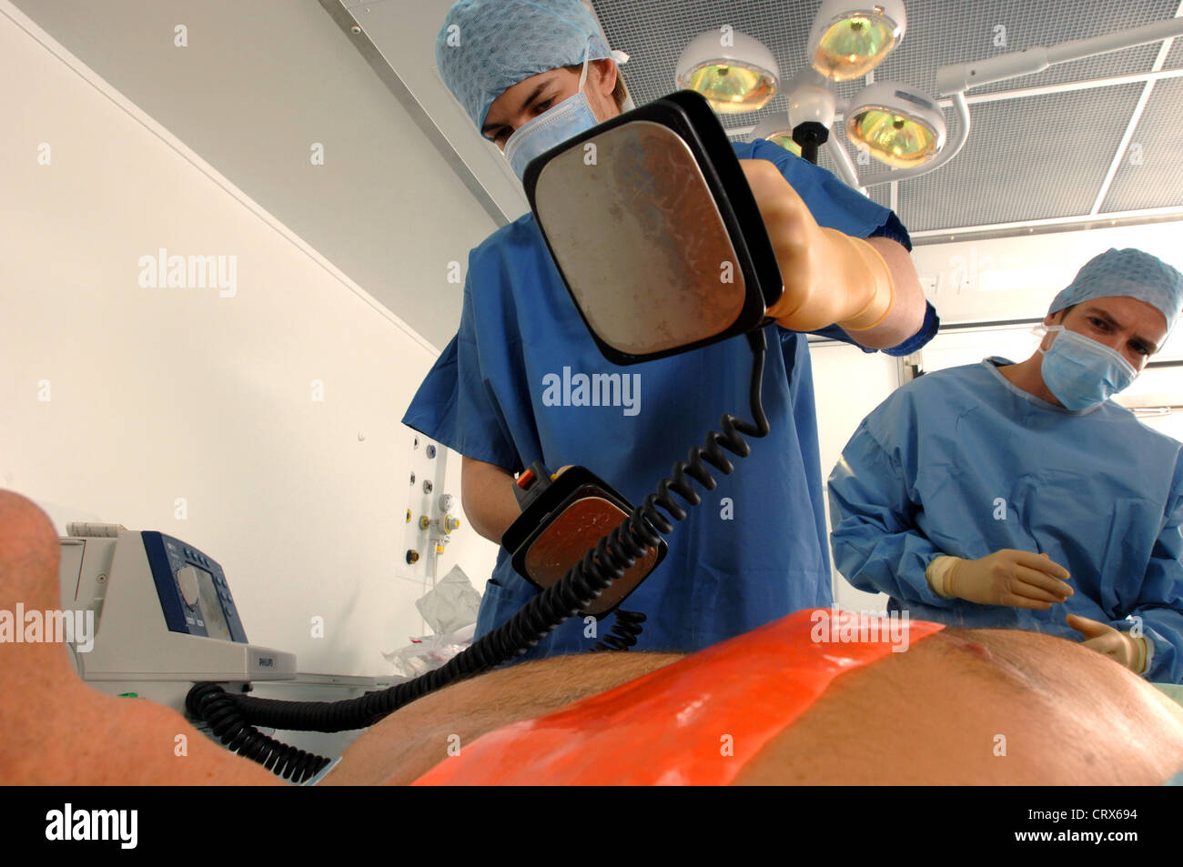I medici utilizzando un defibrillatore per rianimare un maschio di attacco di cuore vittima. Foto Stock