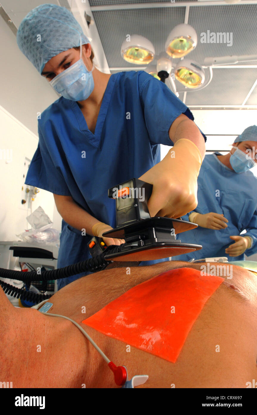 I medici utilizzando un defibrillatore per rianimare un maschio di attacco di cuore vittima. Foto Stock