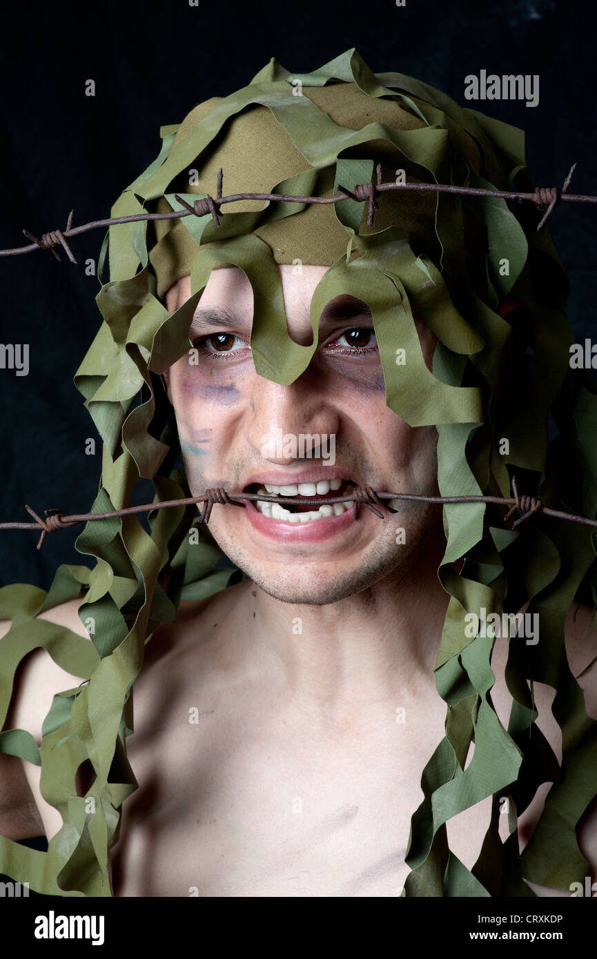 Militare - faccia in primo piano con filo spinato nella sua bocca Foto Stock