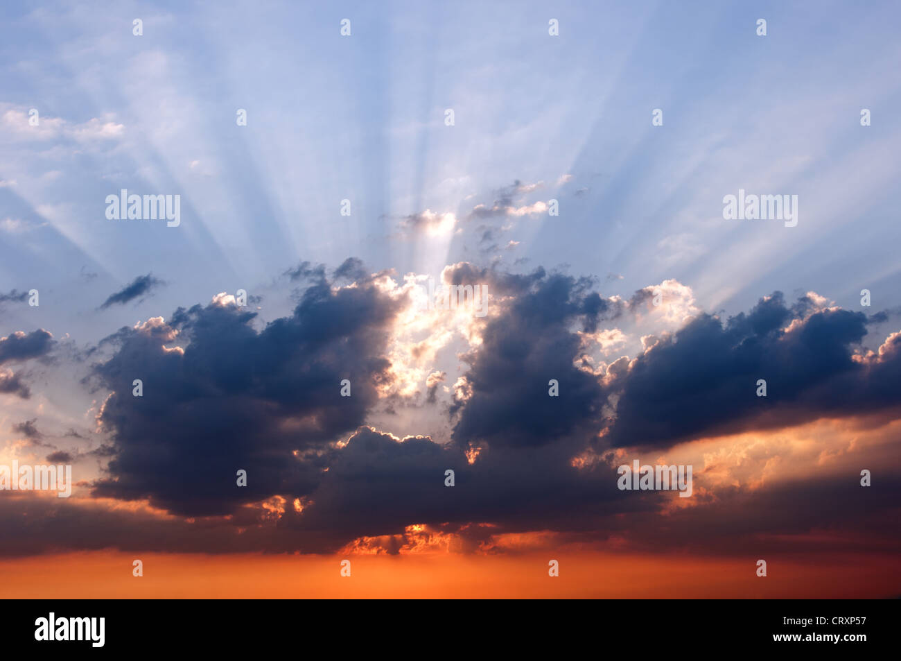 I raggi del sole che tramonta dietro le nuvole e il blu del cielo. Foto Stock