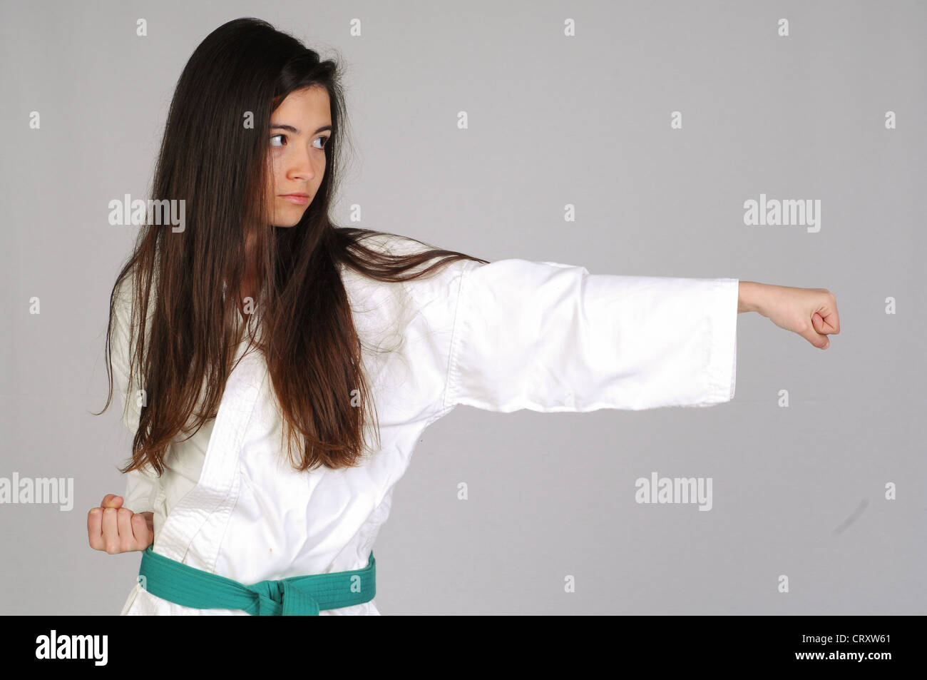 Ragazza nel Karate si muove su uno sfondo grigio Foto Stock