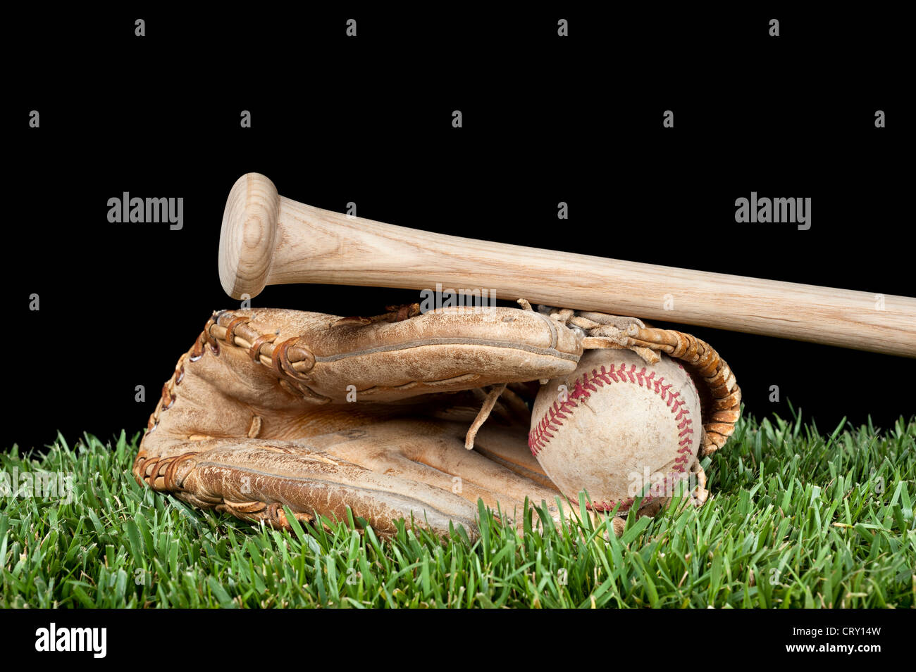 Guanto baseball a sfere, e bat posa su erba con uno sfondo nero per il posizionamento della copia. Foto Stock