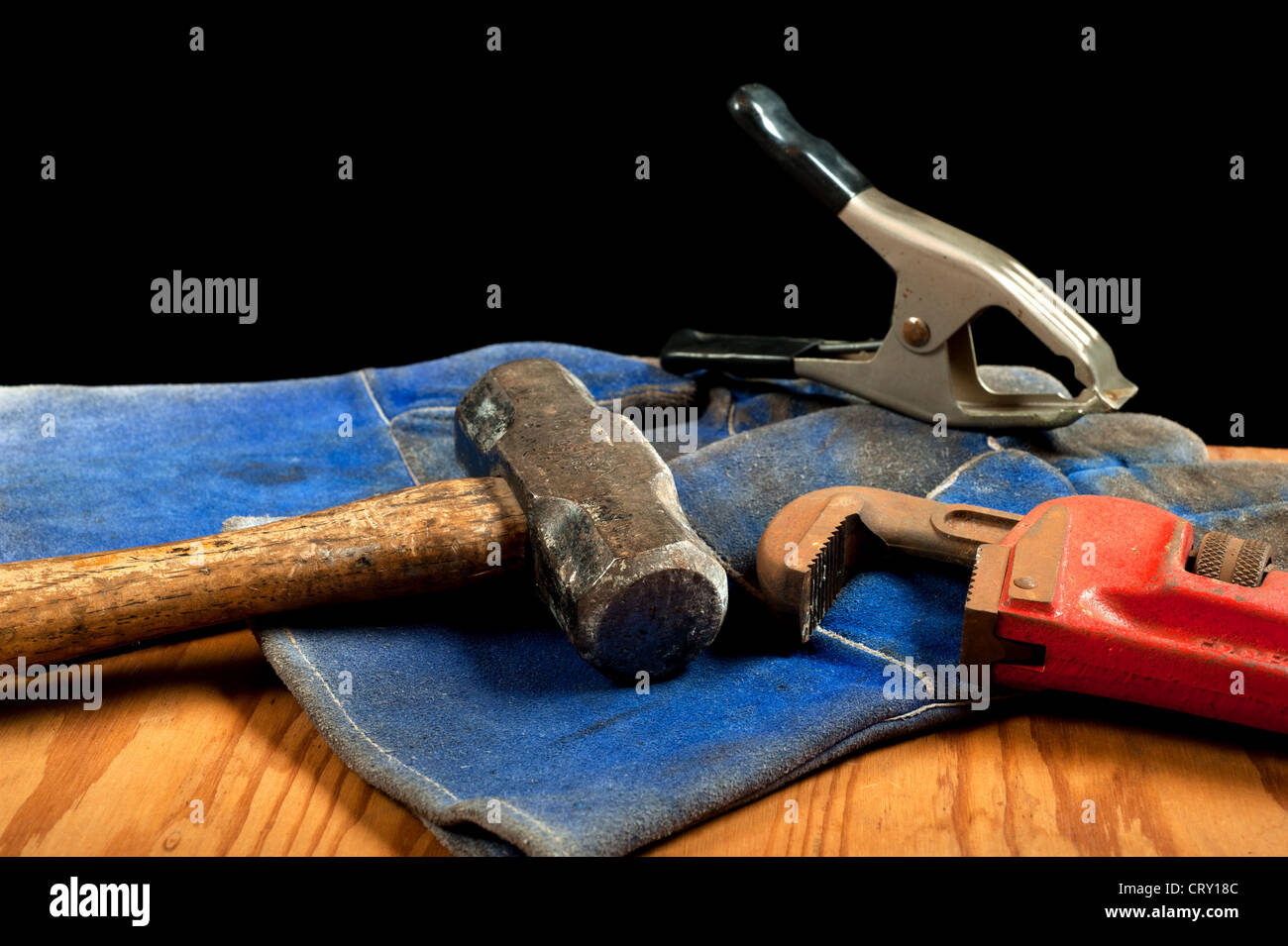 Una schifezza, vecchi utensili comprendente un morsetto, mazza e la chiave a tubo con blu guanti in pelle. Foto Stock