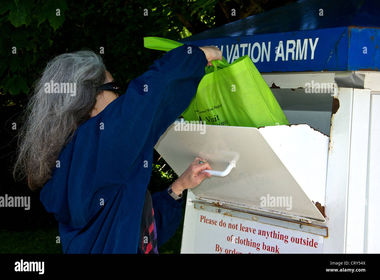Donna collocamento in borsa di indumenti usati nell esercito della salvezza donazione dropoff bin Foto Stock