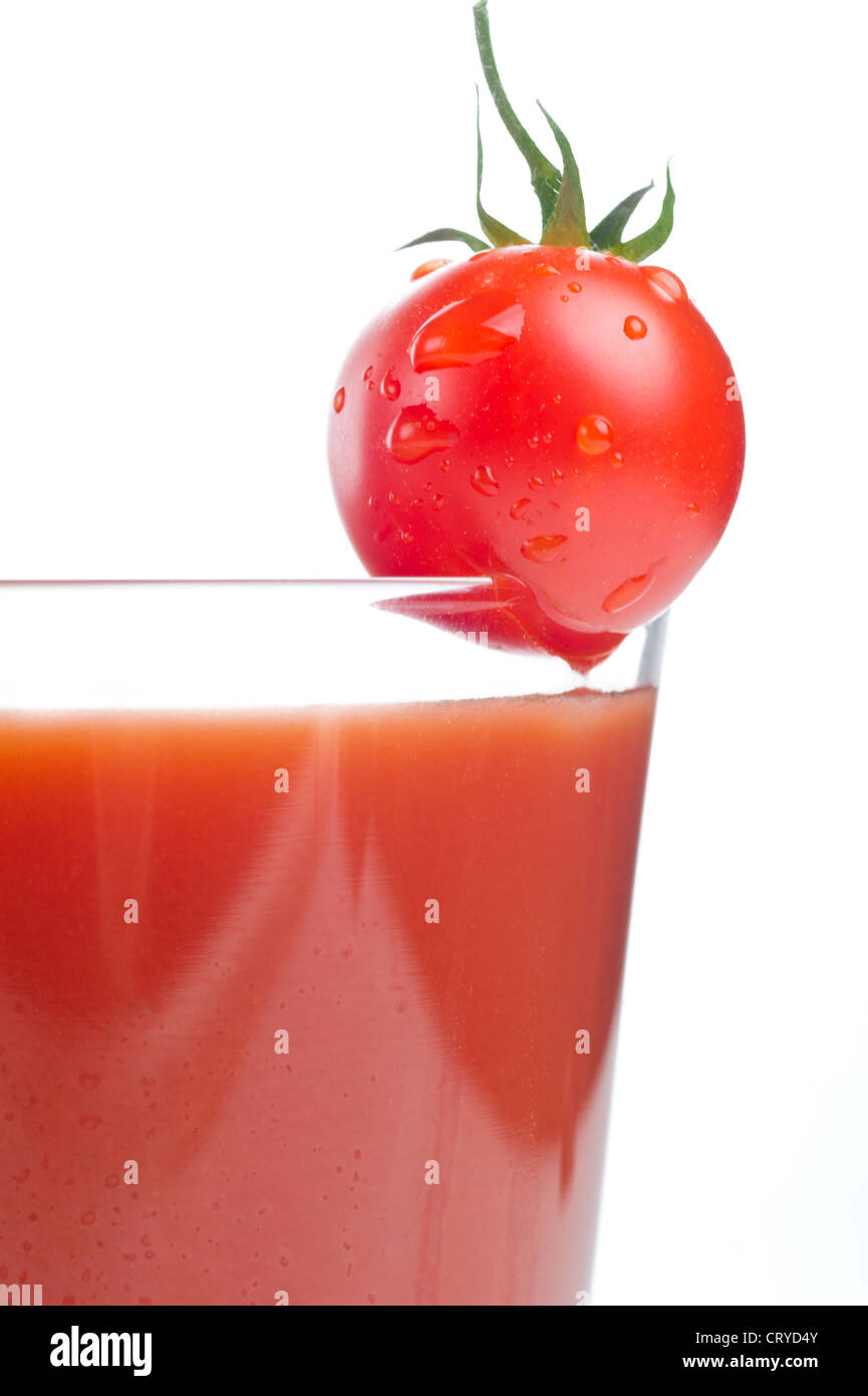 Il succo di pomodoro in un bicchiere e pomodori ciliegini. Isolato su sfondo bianco Foto Stock