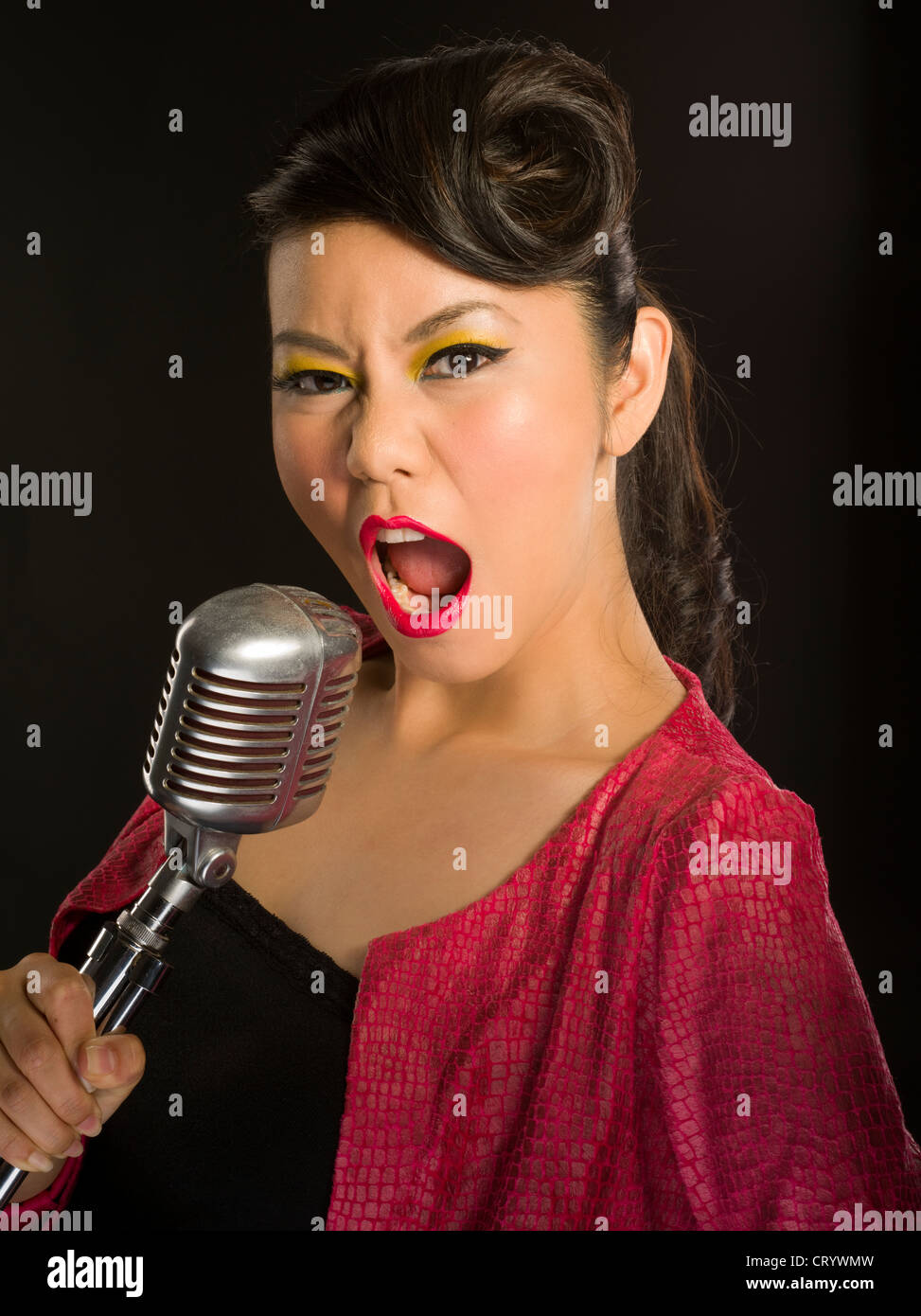 Ragazza asiatica di cantare in un tradizionale stile Elvis Shure microfono Foto Stock