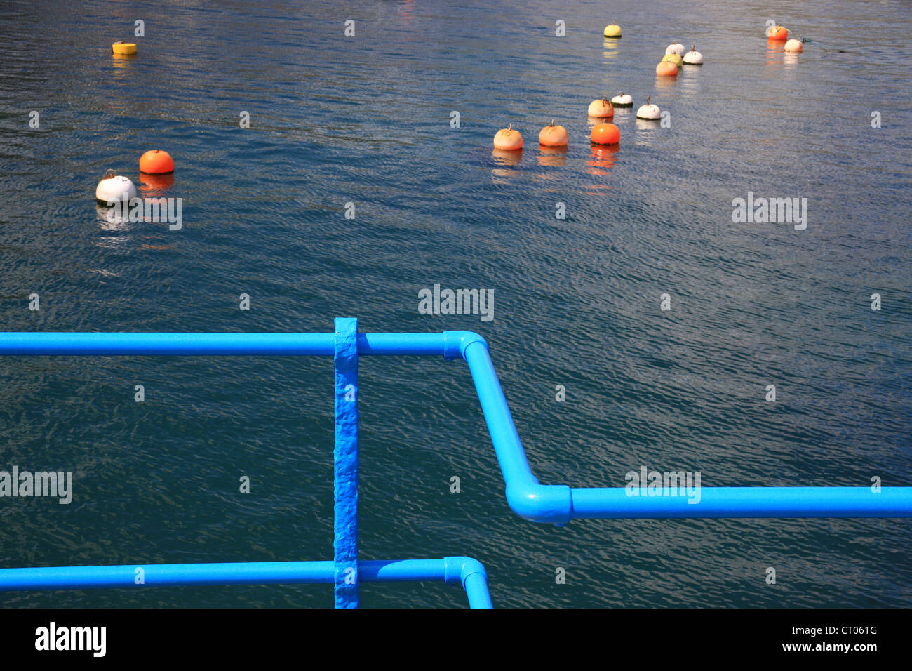 Composizione astratta di arancio e bianco pesca galleggianti e un blu brillante ringhiera in primo piano Foto Stock