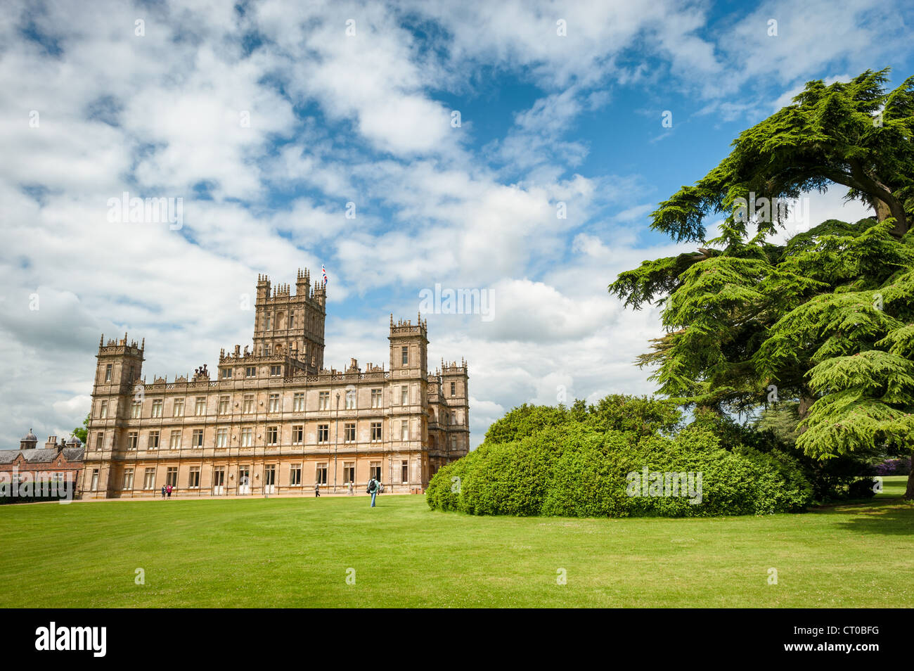 HIGHCLERE CASTLE, Hampshire, Regno Unito: L'iconico Highclere Castle si erge maestosamente in una giornata di sole nella campagna dell'Hampshire. Questa casa di campagna di epoca vittoriana, completata nel 1842, è la casa ancestrale dei conti di Carnarvon e ha guadagnato fama mondiale come location principale per le riprese della serie televisiva Downton Abbey. Il castello in stile Jacobethan presenta una caratteristica pietra di Bath color miele ed è stato progettato dall'architetto Sir Charles Barry, che ha anche progettato il Parlamento. Circondata da circa 1.000 acri di parco, la tenuta include giardini originariamente de Foto Stock