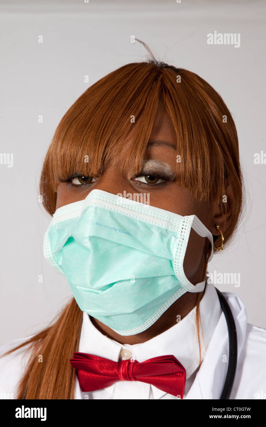 Bella femmina lavoratore di cura di salute in una mascherina chirurgica e un rosso il filtro bow tie, guardando il caemra Foto Stock