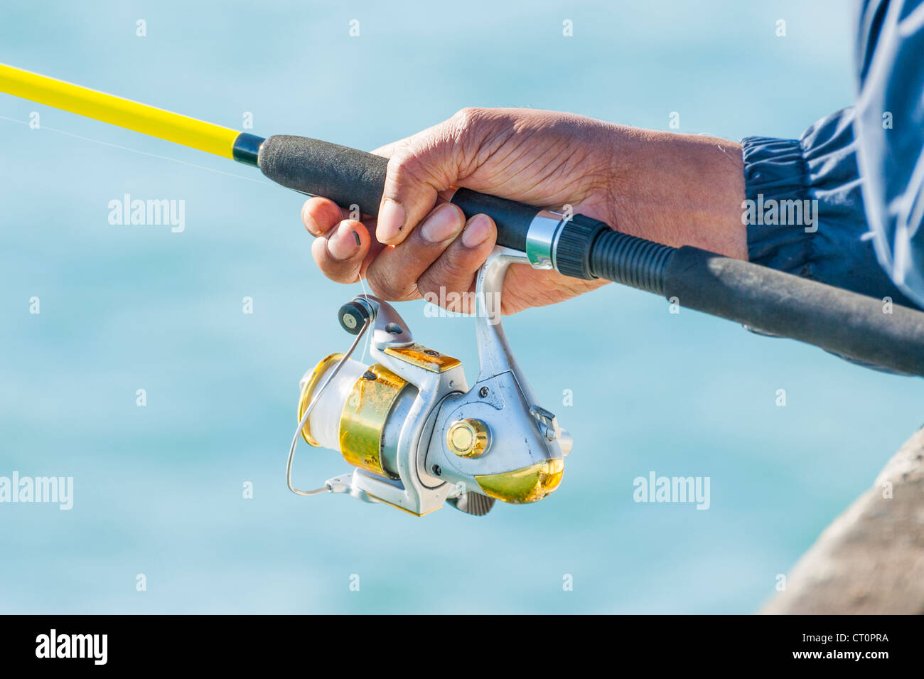 Close up di un uomo in possesso di un giallo canna da pesca. Foto Stock