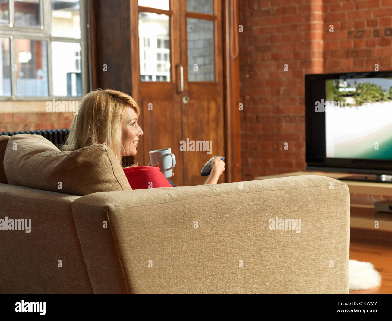Donna di guardare la televisione sul divano Foto Stock