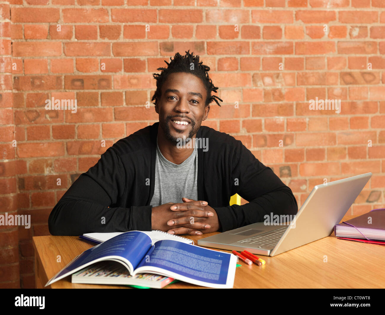 Uomo sorridente studiando con il computer portatile Foto Stock