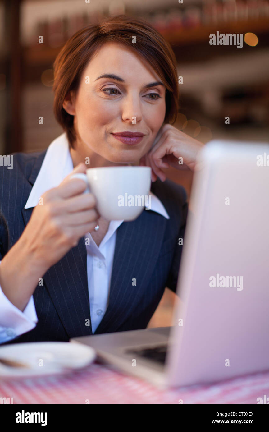 Imprenditrice utilizzando laptop in cafe Foto Stock