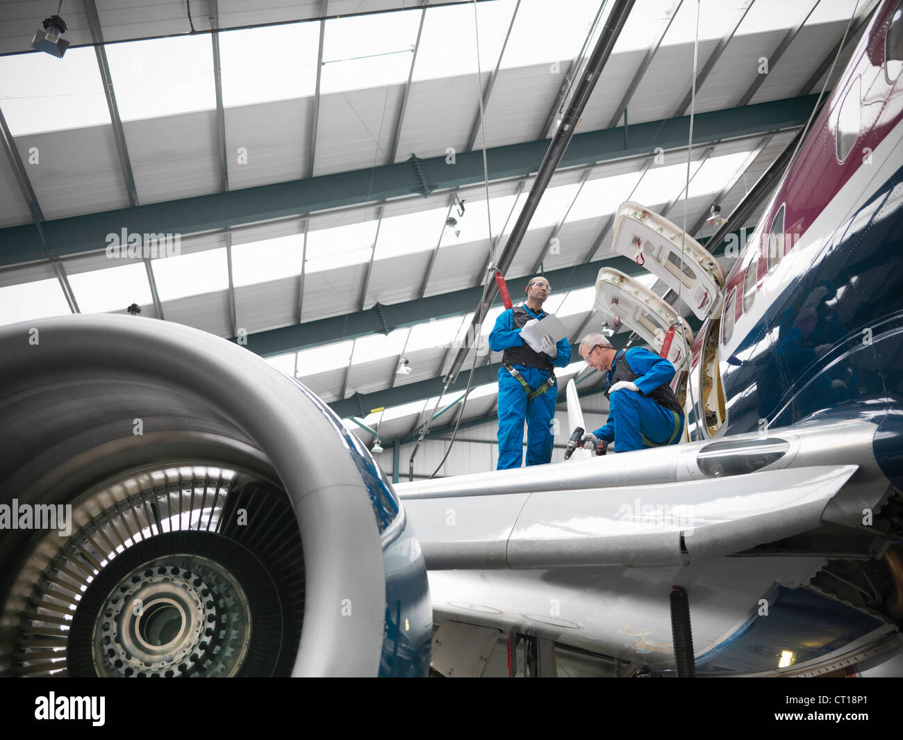Lavoratori esaminando ala di aeroplano Foto Stock