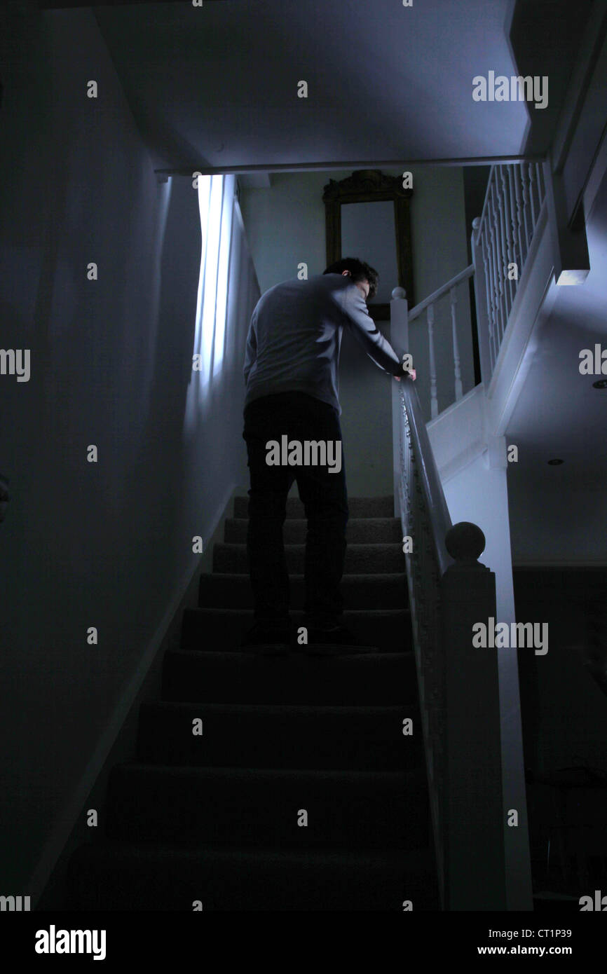 Vista posteriore di un giovane maschio al piano di sopra a piedi nel buio. Foto Stock