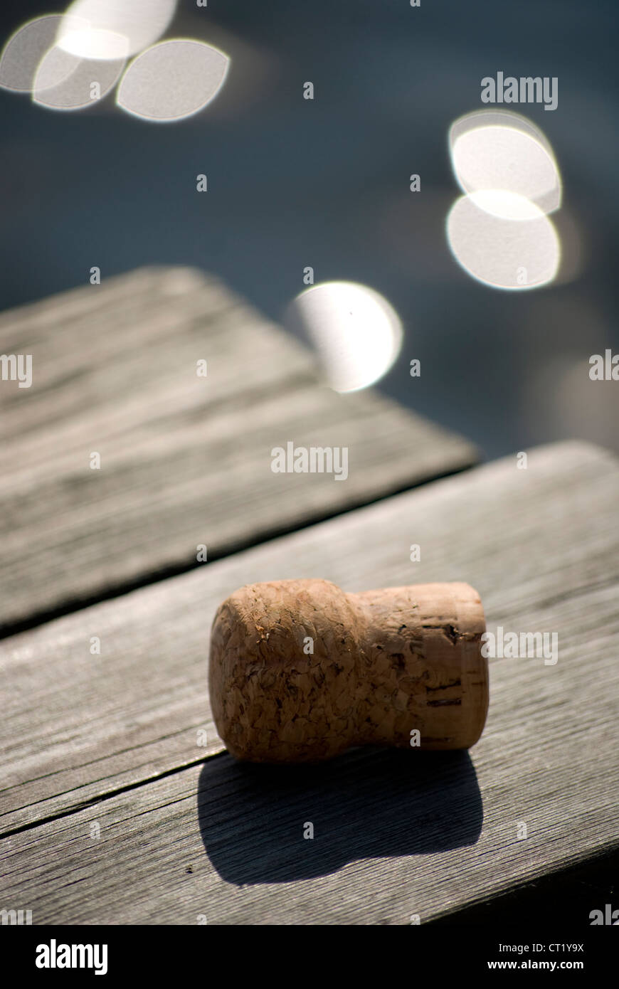 Tappo per bottiglia di vino sul molo, acqua con sun la riflessione in background Foto Stock