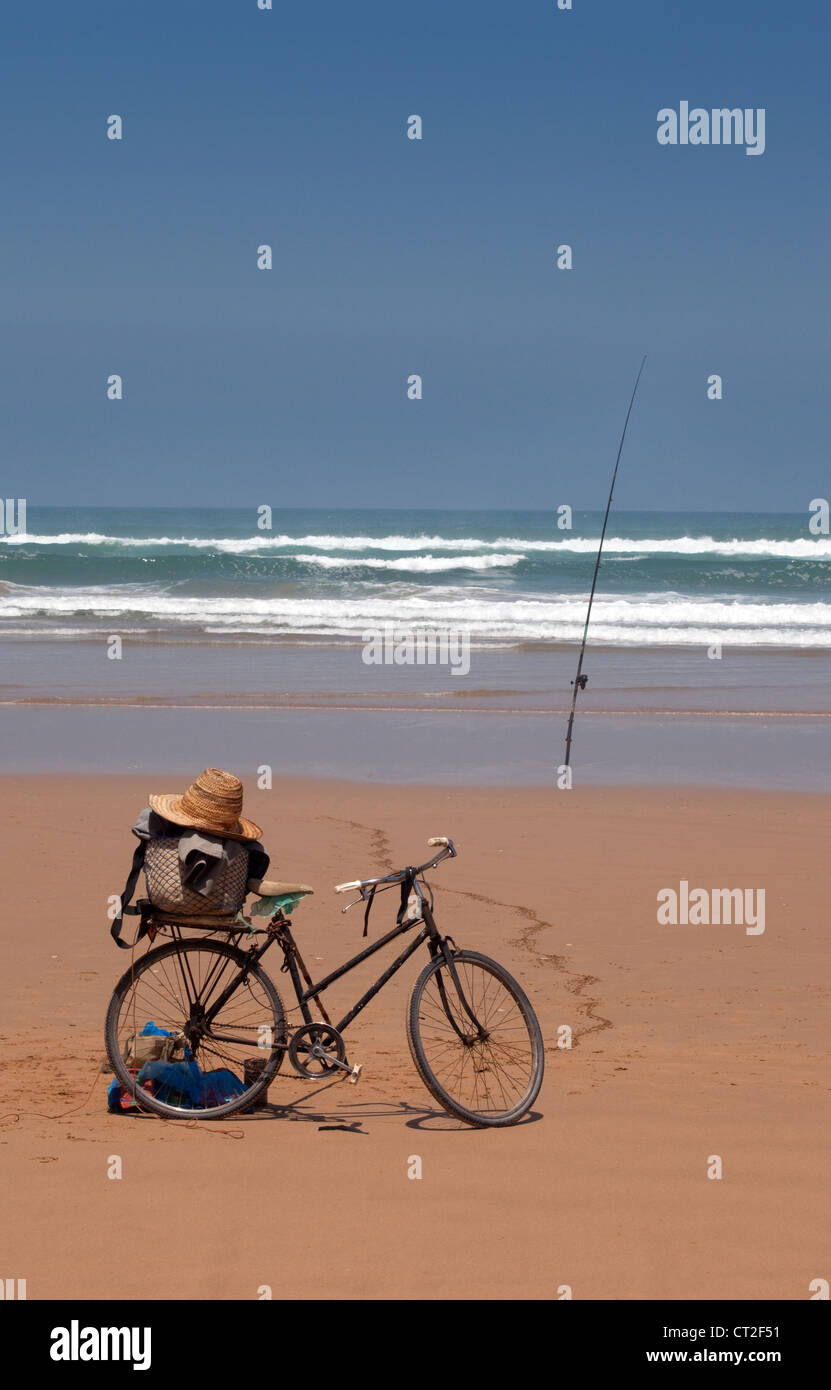Spiaggia africana; una bicicletta di pescatori e canna da pesca sulla spiaggia vicino Agadir, marocco Africa Foto Stock