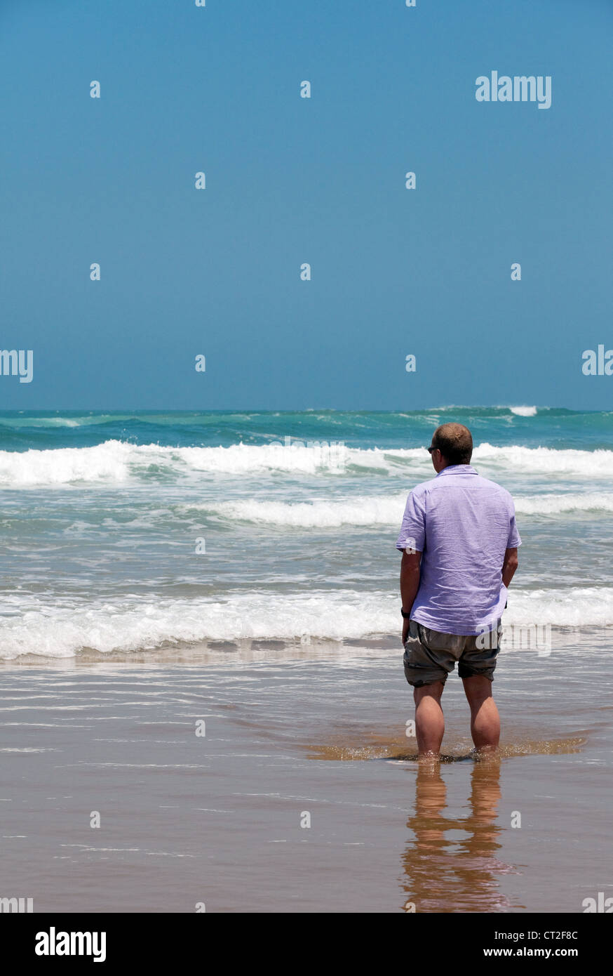 Un uomo in piedi sul bordo dell'Oceano Atlantico sulla spiaggia vicino a Agadir, Marocco Foto Stock