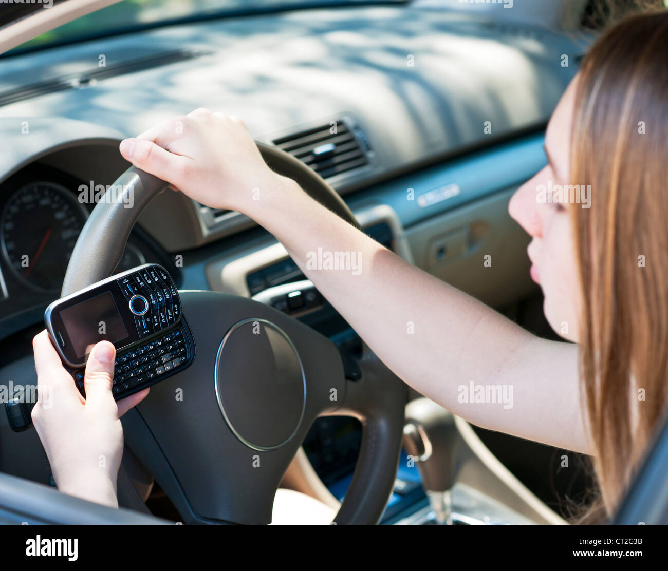 Ragazza adolescente sms sul cellulare durante la guida Foto Stock