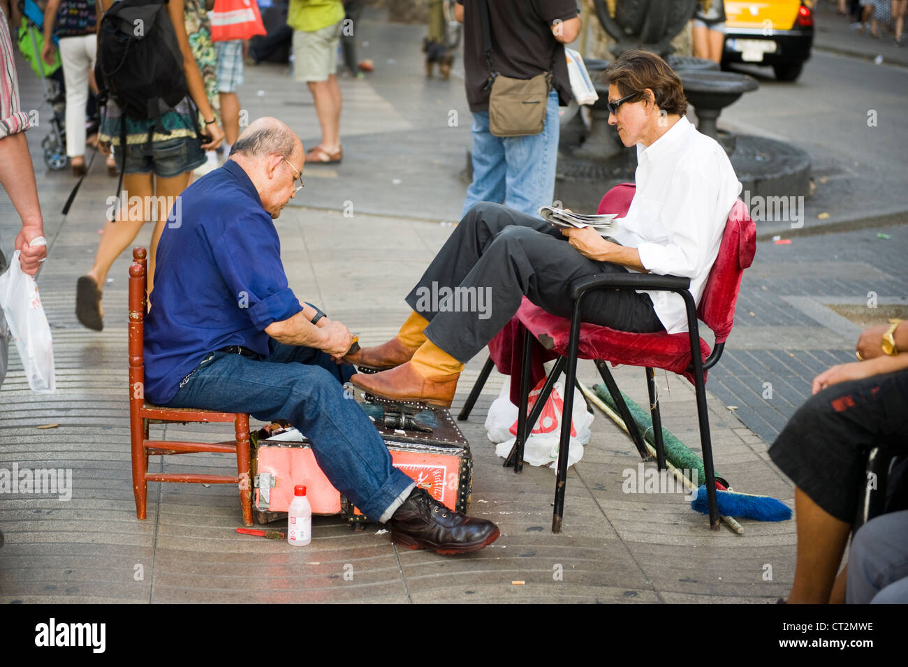 Venditore ambulante sciuscià fornendo un lustrascarpe al client sulla Rambla di Barcellona Foto Stock