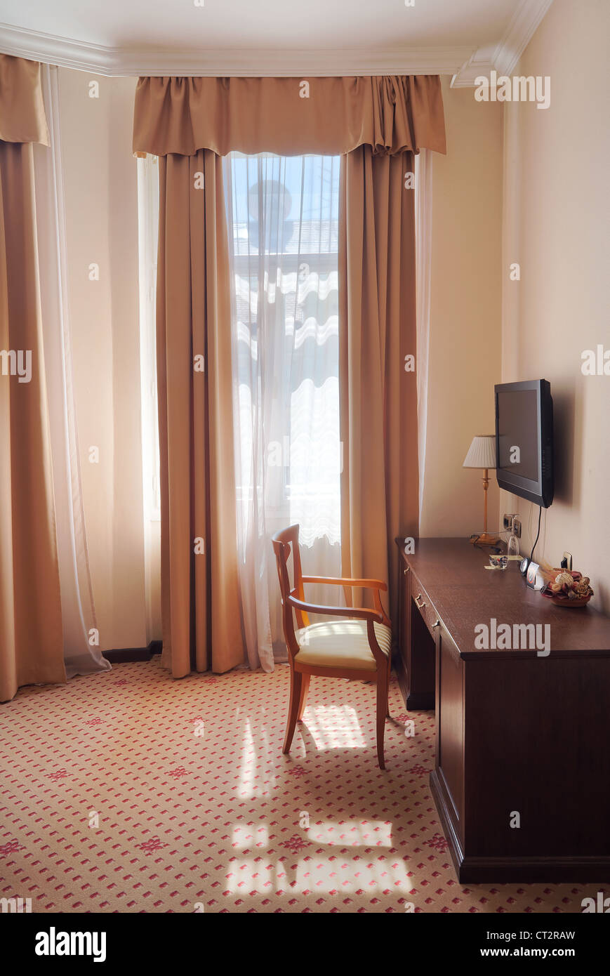 Una parte di un hotel appartamento, in stile vintage, solo una sedia vicino alla finestra. Foto Stock