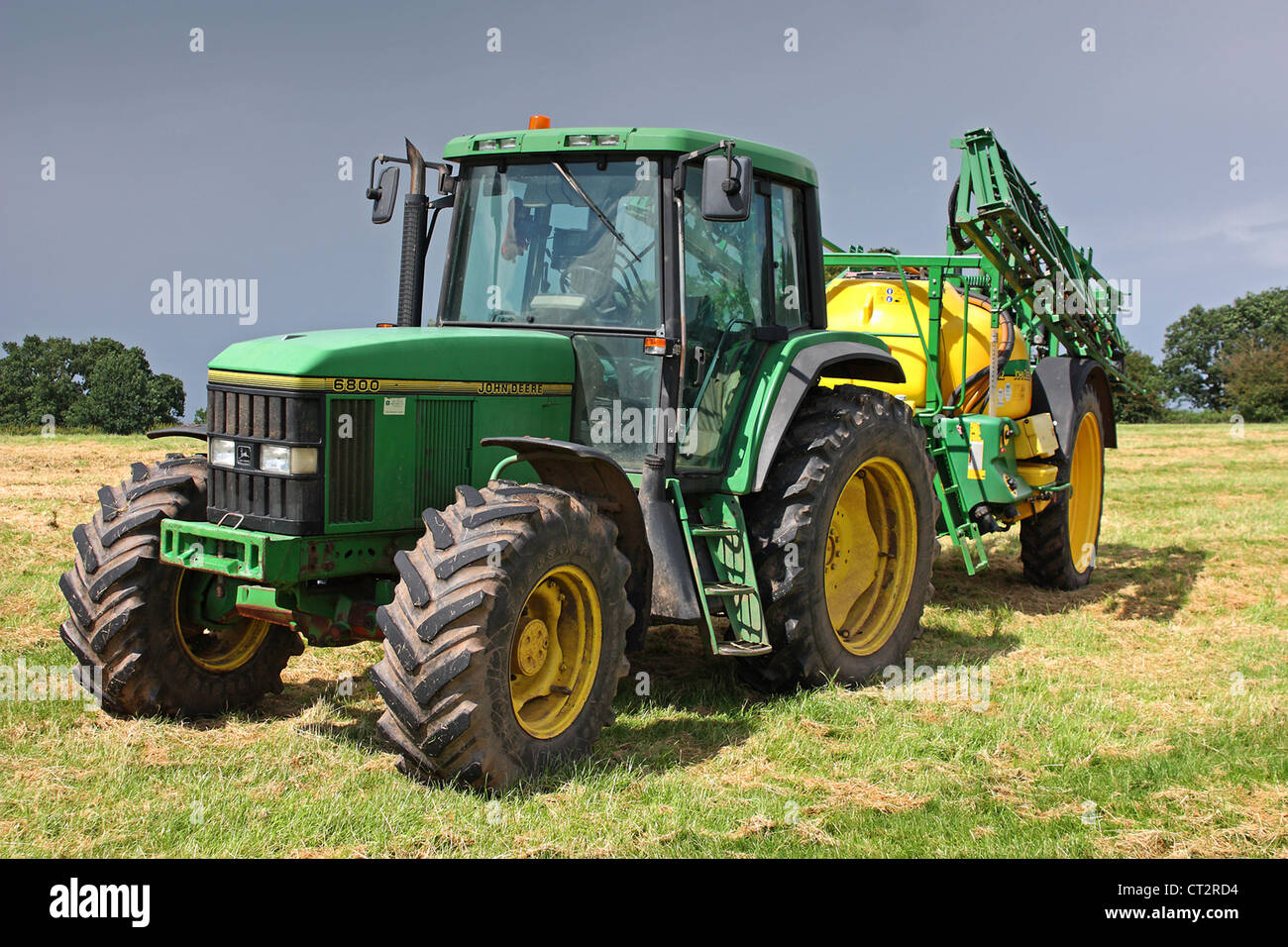 Una foto di un trattore tirando alcune attrezzature agricole Foto Stock