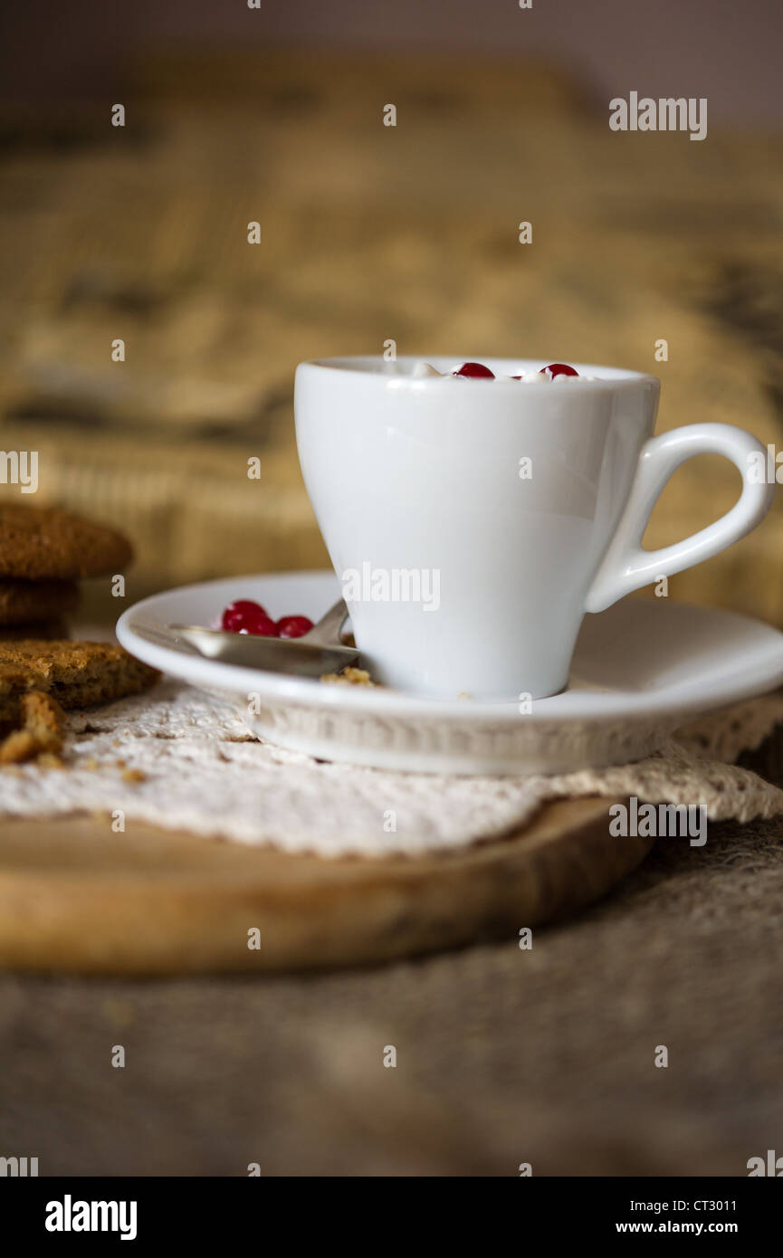 Sbriciolare oat cookies biscotti con caffè caldo e panna montata con mirtilli rossi sulla parte superiore. DOF poco profondo Foto Stock