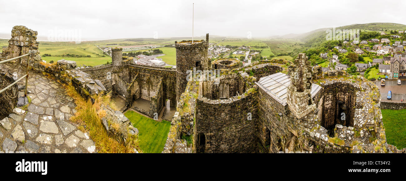 HARLECH, Galles: Una vista panoramica dalle merlature del castello di Harlech rivela le torri storiche, la città circostante, la campagna e Tremadog Bay in lontananza. Costruito tra il 1282 e il 1289 da Edoardo i durante la sua conquista del Galles, questo sito patrimonio dell'umanità dell'UNESCO si erge come uno dei migliori esempi di architettura militare della fine del XIII secolo in Europa. La posizione strategica del castello in cima a un affioramento roccioso forniva ai difensori una vista dominante sui potenziali approcci. Il castello di Harlech faceva parte dell'"anello di ferro" di Edoardo i di fortezze progettate per accerchiare e controllare il Galles del Nord. Nonostante Foto Stock