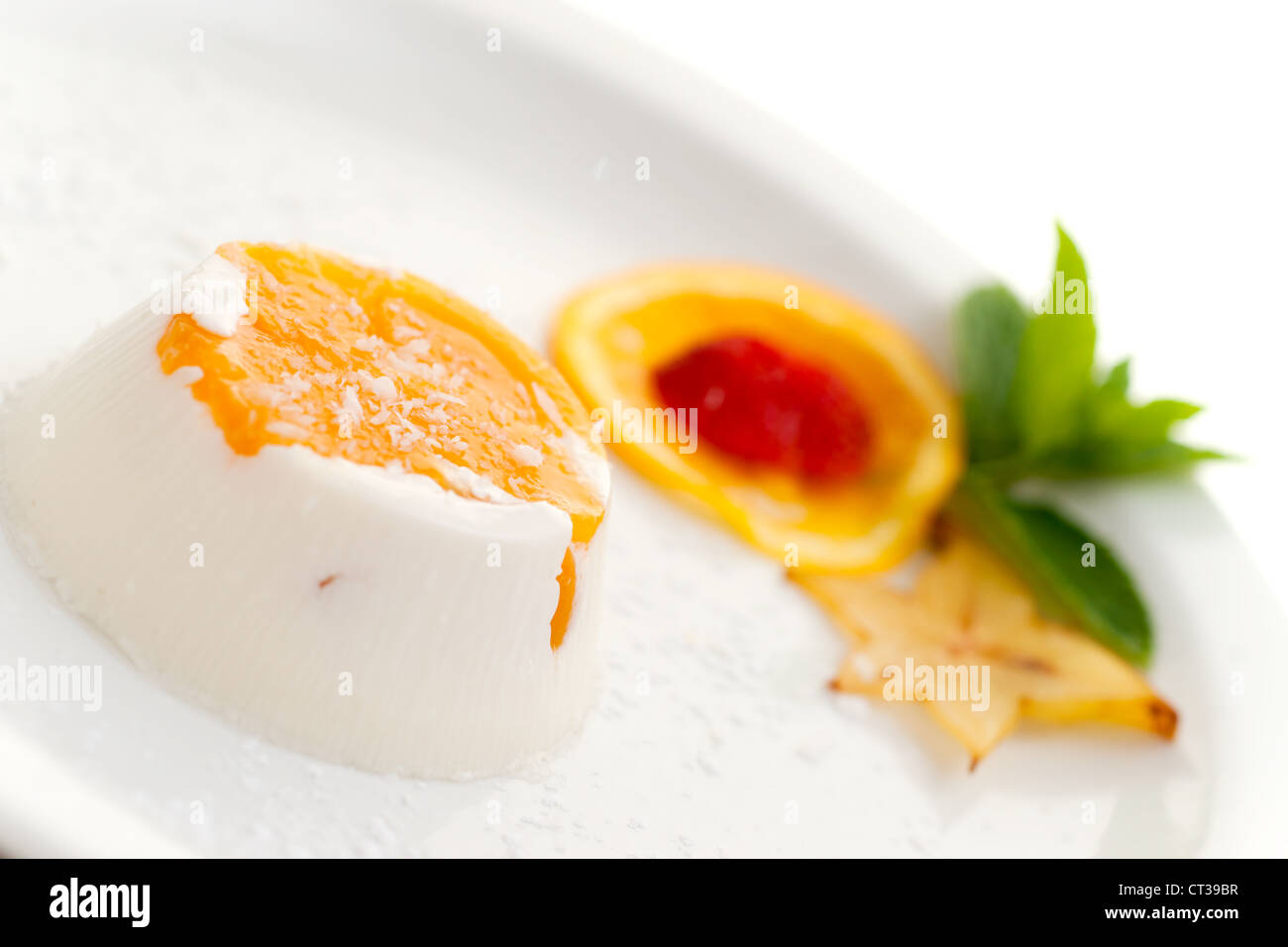 Dolce italiano panna cotta su piastra bianca decorata con latte di cocco e pesca. Foto Stock