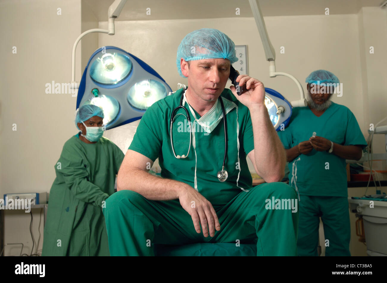Un chirurgo utilizzando il suo telefono cellulare in tra le procedure. Foto Stock