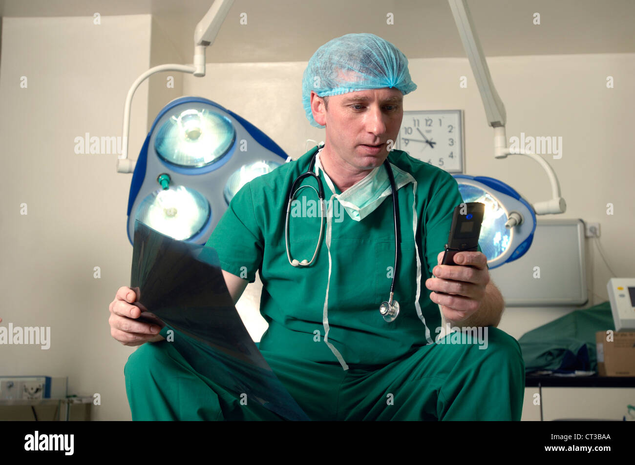 Un chirurgo in una discussione telefonica con un collega su un paziente di raggi x. Foto Stock