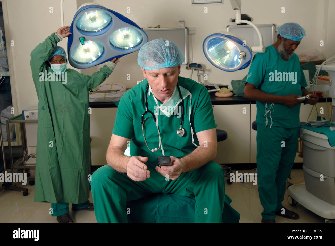 Un chirurgo controllo dei messaggi sul suo telefono cellulare Foto Stock
